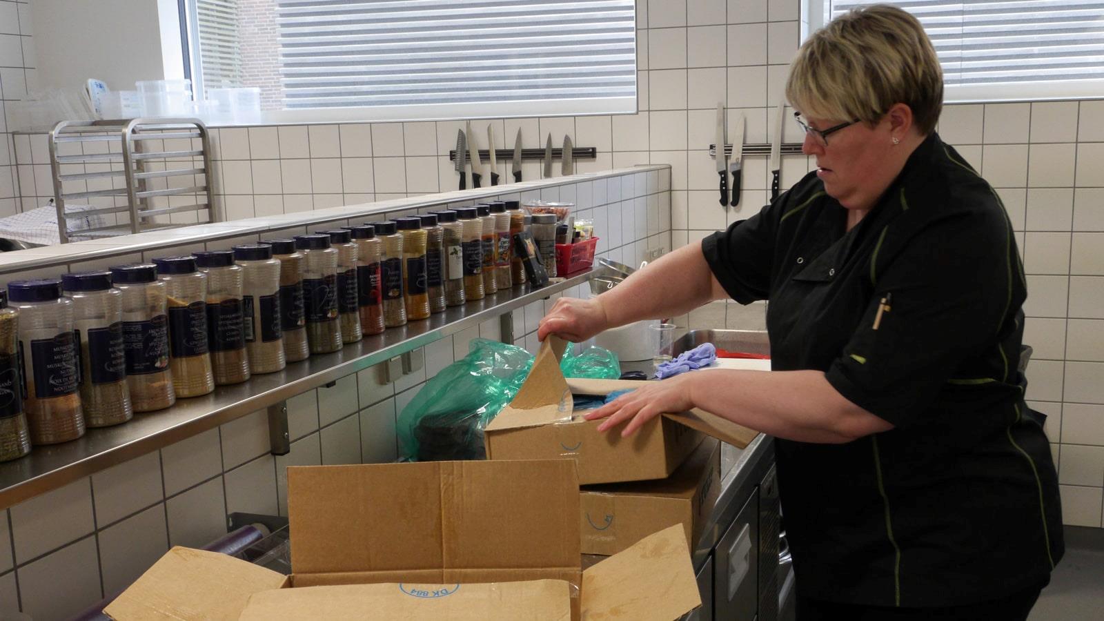 Canteen employee opening cardboard boxes with Tulip meat products