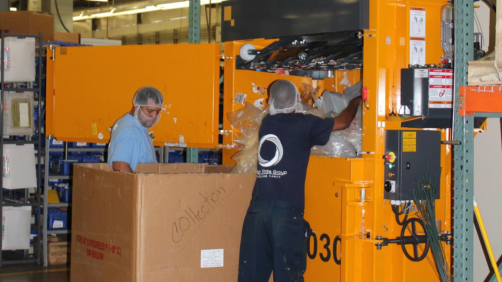 Two employees put plastic wrap into vertical baler from Bramidan